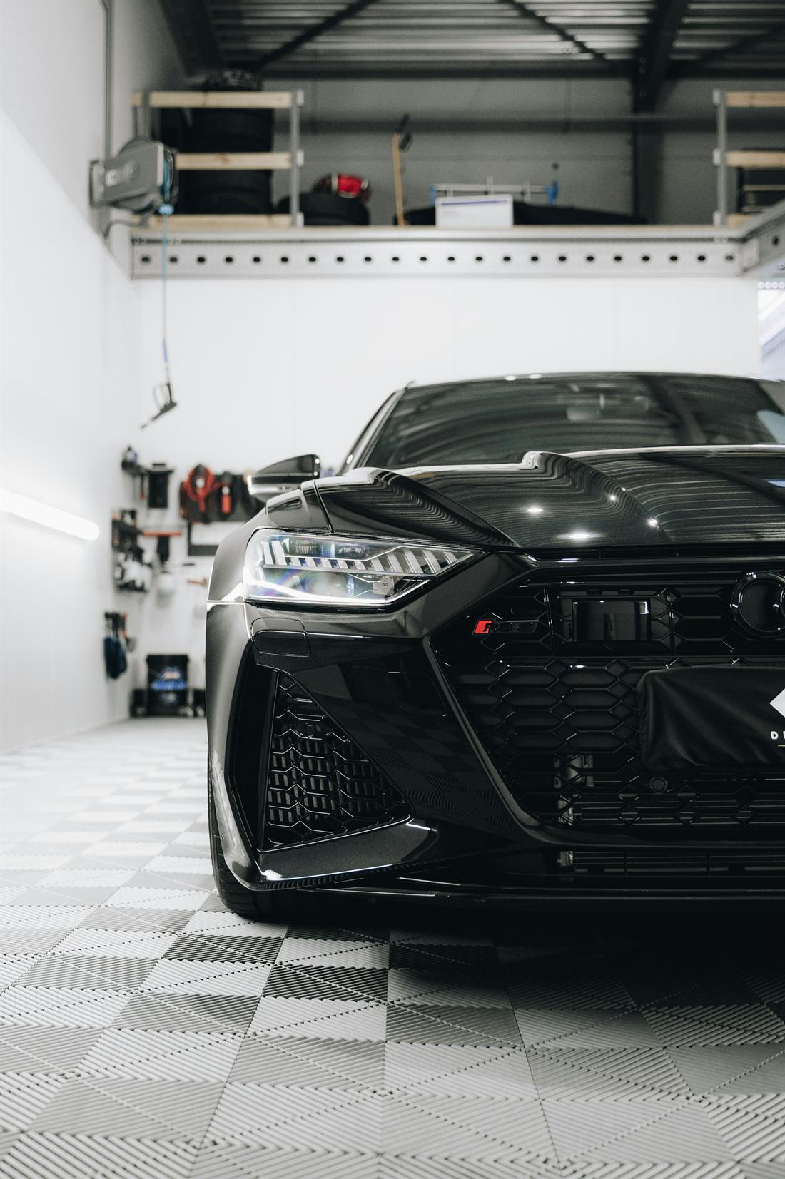Black performance car with a gloss finish parked in a bright detailing bay