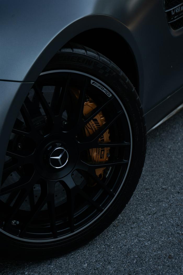 Dark alloy wheel with orange brake caliper on a grey performance car