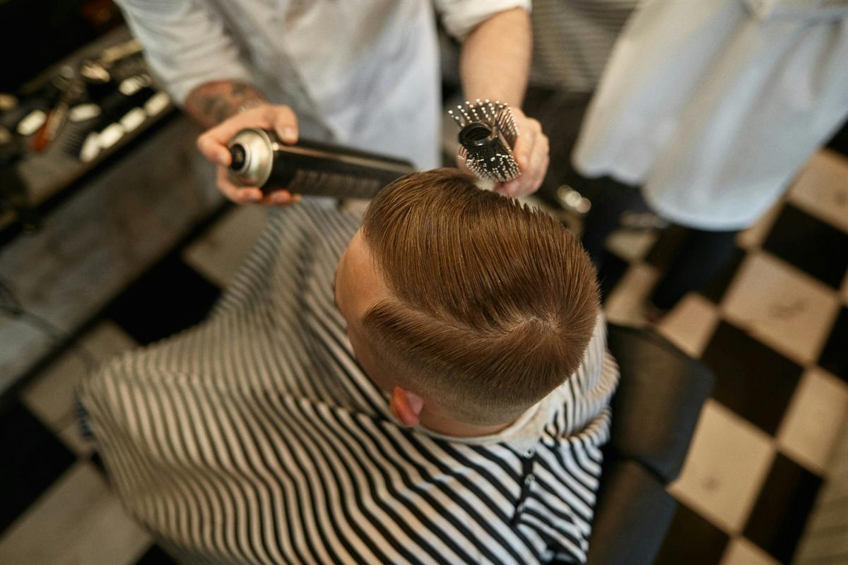 Overhead view of a tapered side-parted haircut being styled with a round brush