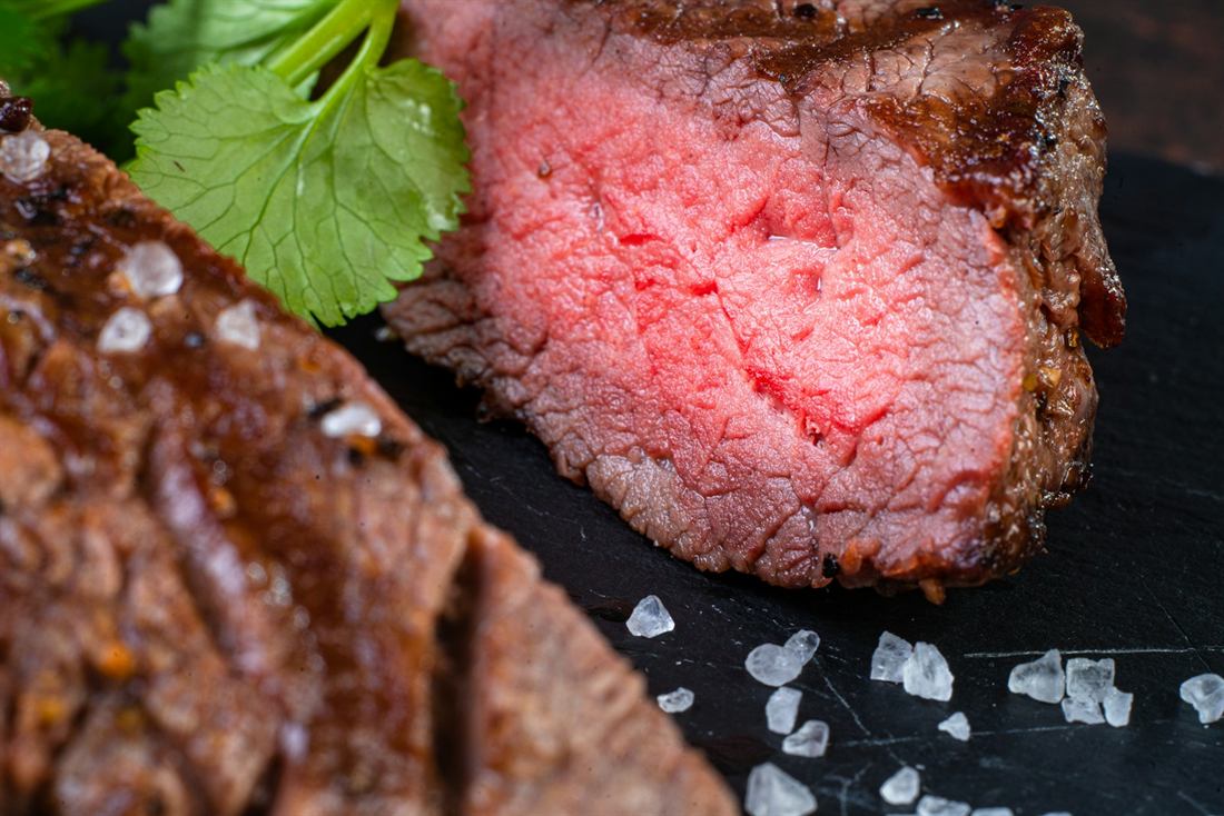 Sliced slow-roasted lamb, rosy in the centre with a dark crust, served on slate