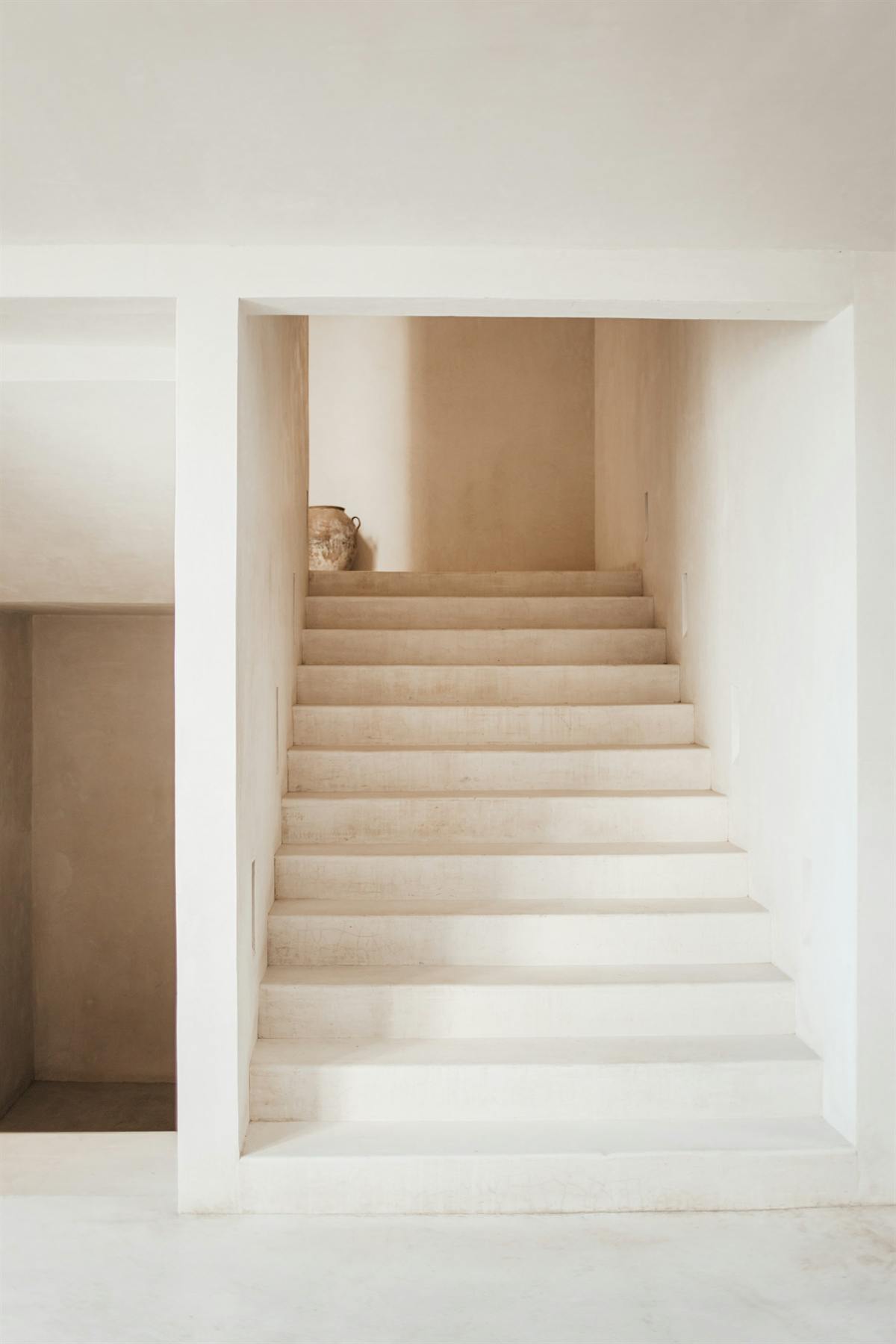 A pale plaster staircase rising to a small landing